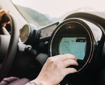 Man sitting in the car with black interior and looking at the new route laid by the navigator. Driver waiting for the itinerary to be made up before journey.