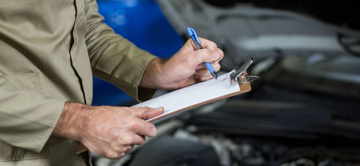 Mid-section of mechanic preparing a check list